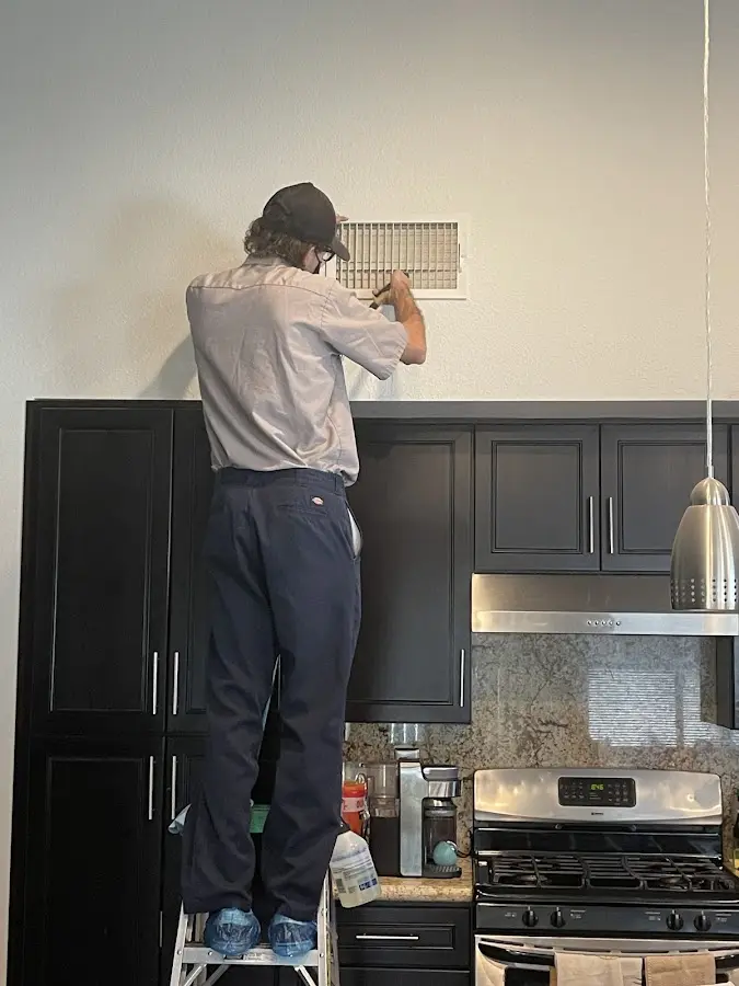 Technician inspecting an air vent during HVAC service in Concord